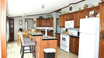 A kitchen with wooden cabinets, a central island, a microwave, and a refrigerator.