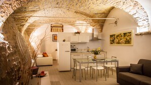 A compact living space with a kitchen, dining area, and a sofa. - Housing with private garden terrace and residential swimming pool (Liguria)