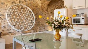 A kitchen with a stone wall, a white refrigerator, a microwave, and a vase with flowers on the table. - Housing with private garden terrace and residential swimming pool (Liguria)