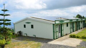 A single-story building with a flat roof, solar panels, and a green door. - Sea view house (bois de nèfles st paul)
