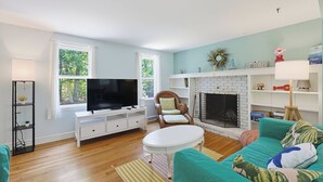 Ein Wohnzimmer mit Fernseher, Kamin, Sofa und Sessel.