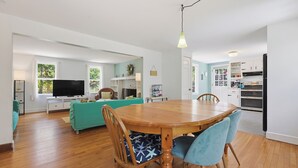 Ein geräumiges Wohnzimmer mit einem Holzespeisetisch, einem türkisfarbenen Sofa und einem Fernseher.