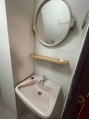 Een badkamer met een wit wastafelmeubel, een spiegel en een plank.