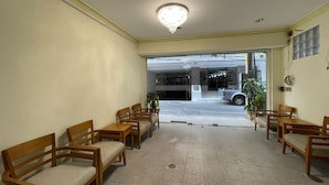 A hotel lobby with wooden chairs and tables, a chandelier, and a view of the street outside. - Residence inn (Pattaya)