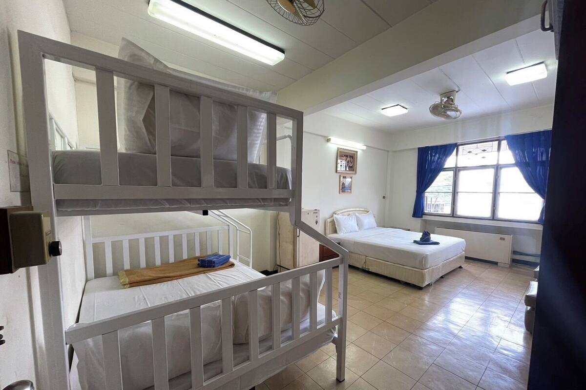 A hospital room with a bunk bed, a single bed, and a window with curtains.
