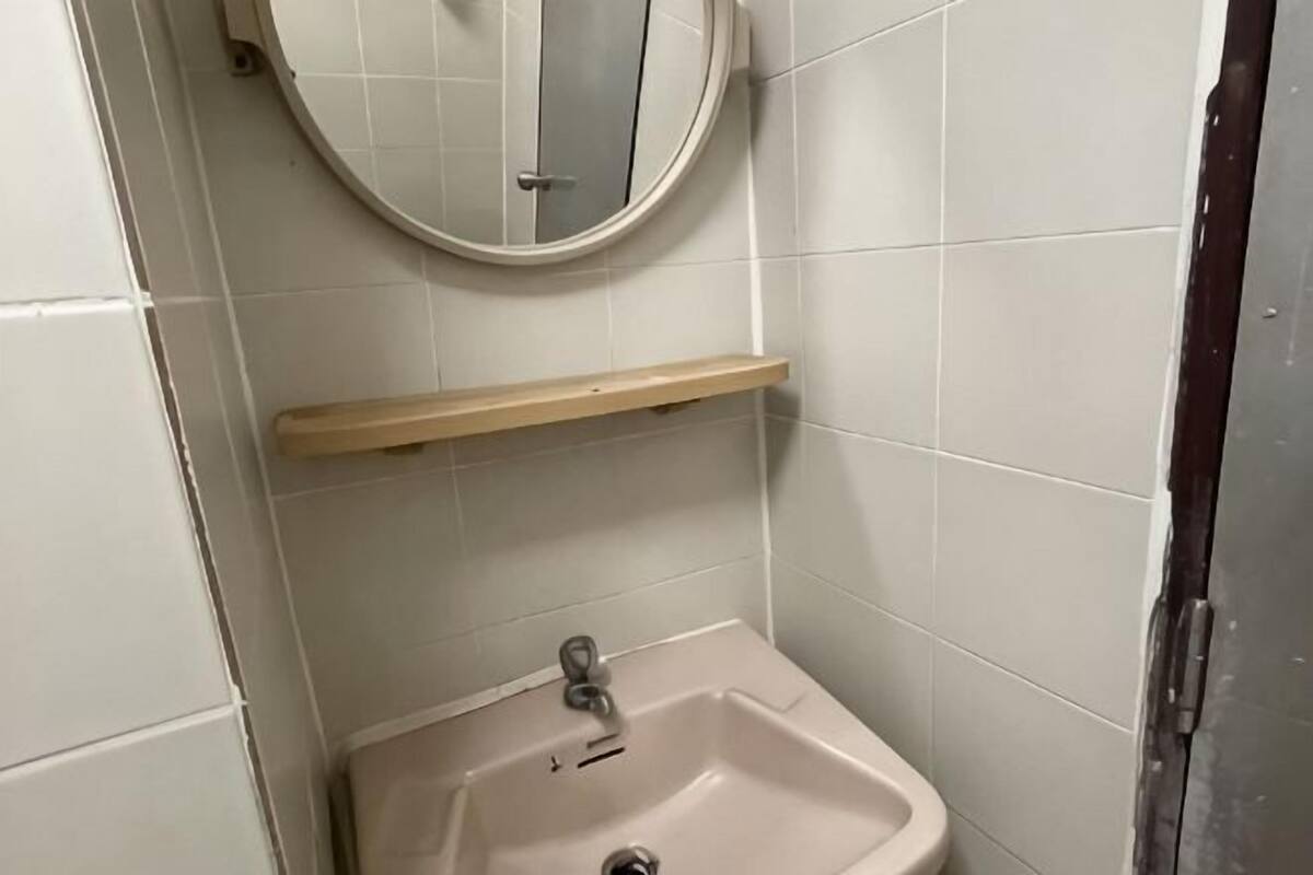 A bathroom with a sink, a mirror, and a shelf.