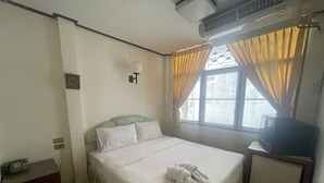 A hotel room with a bed, a bedside table, a TV, and a window with curtains. - Residence inn (Pattaya)