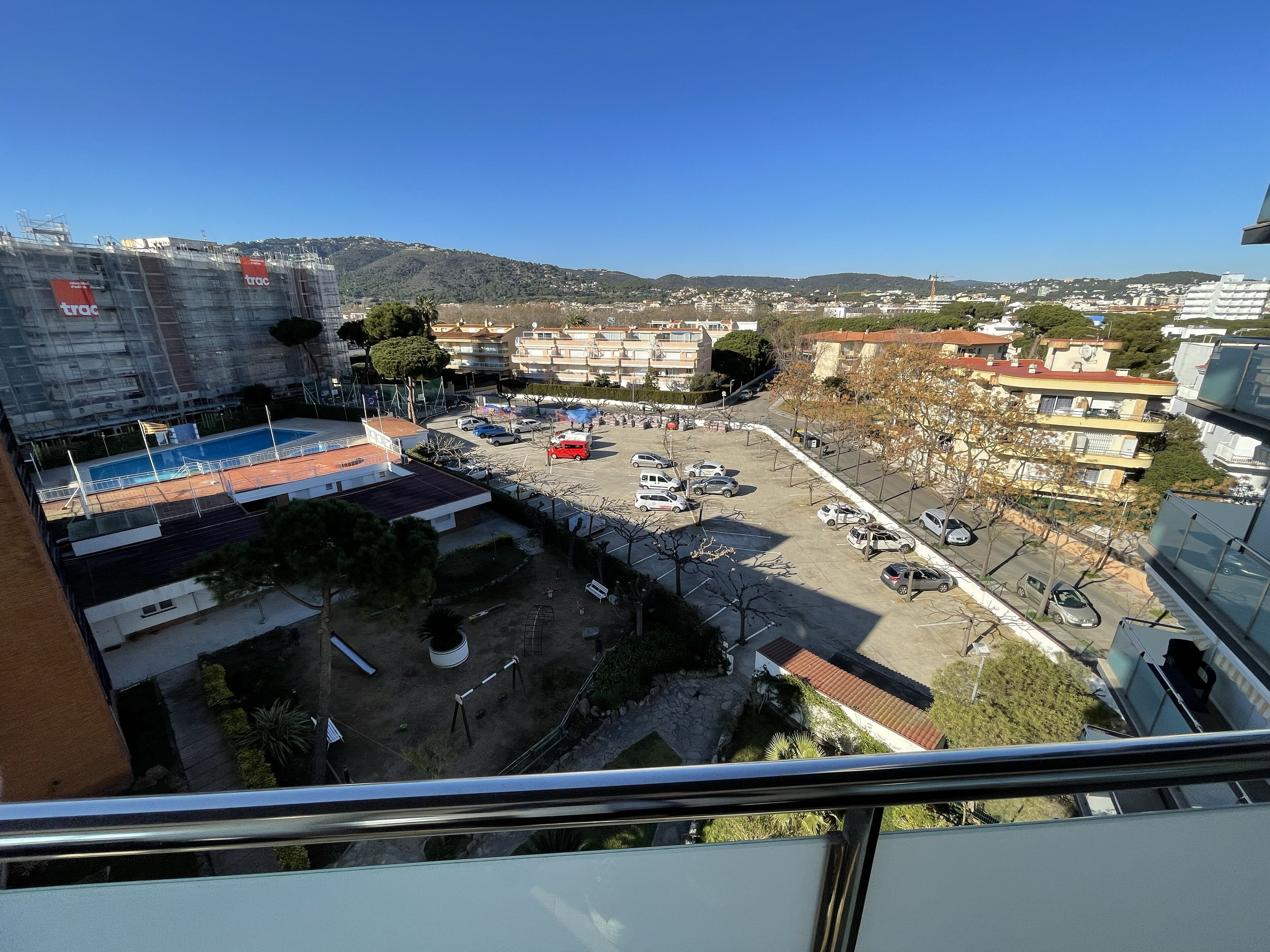 Zona residencial con piscina, aparcamiento y edificios.