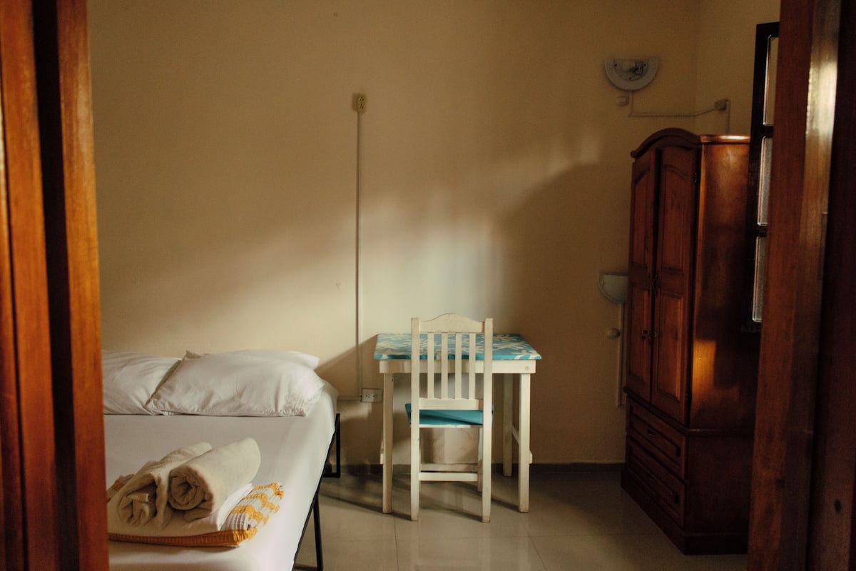 A room with a bed, a wooden chair, a desk, and a wardrobe.