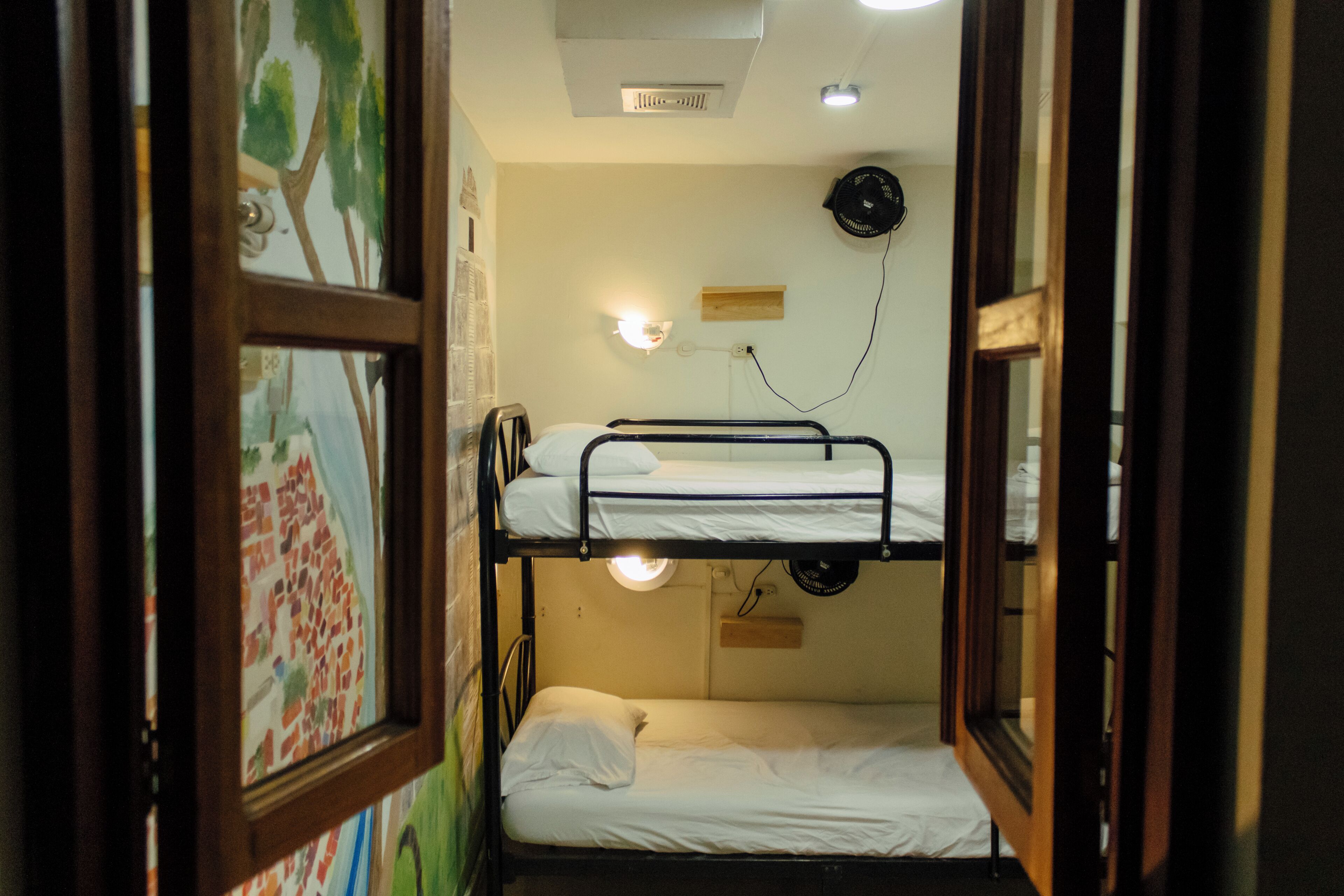 A bunk bed room with a ceiling fan, wall-mounted light, and a framed picture on the wall.