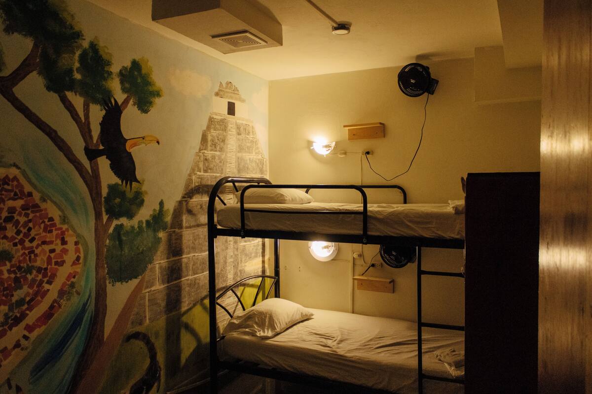 A bunk bed room with a mural, a wall-mounted fan, and a light fixture.