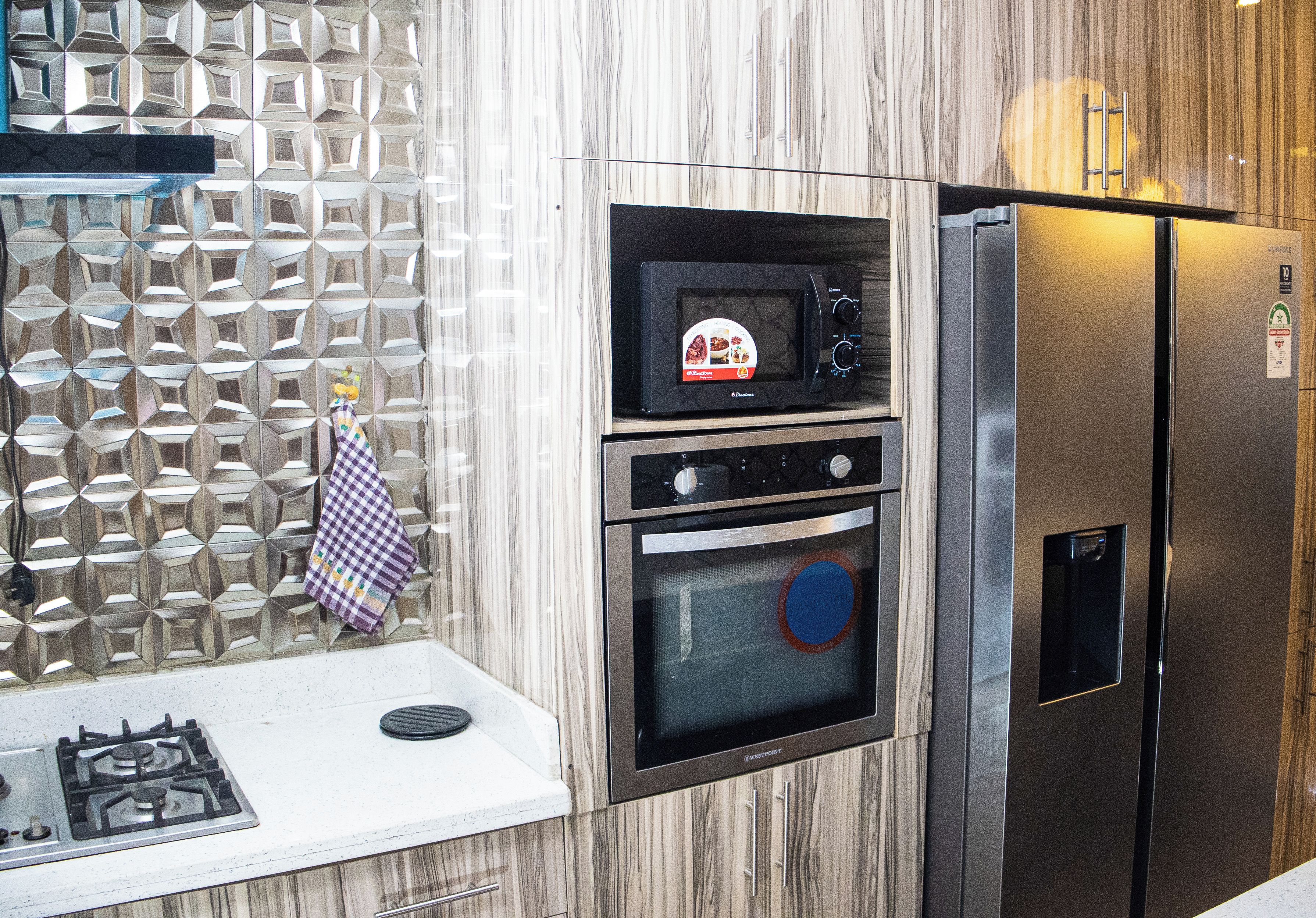 Una cocina equipada con microondas, horno y refrigerador.