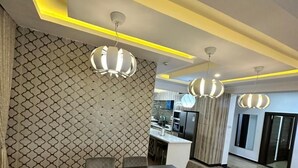 A modern dining area with a rectangular table and six chairs, a patterned wall, and pendant lighting. - Nigus House Oniru (Lagos)