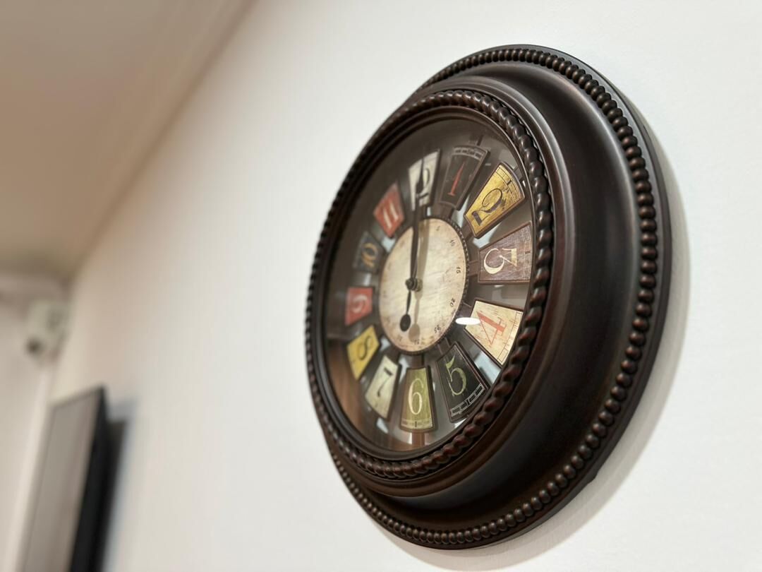 A wall-mounted clock with a circular face and a decorative frame.