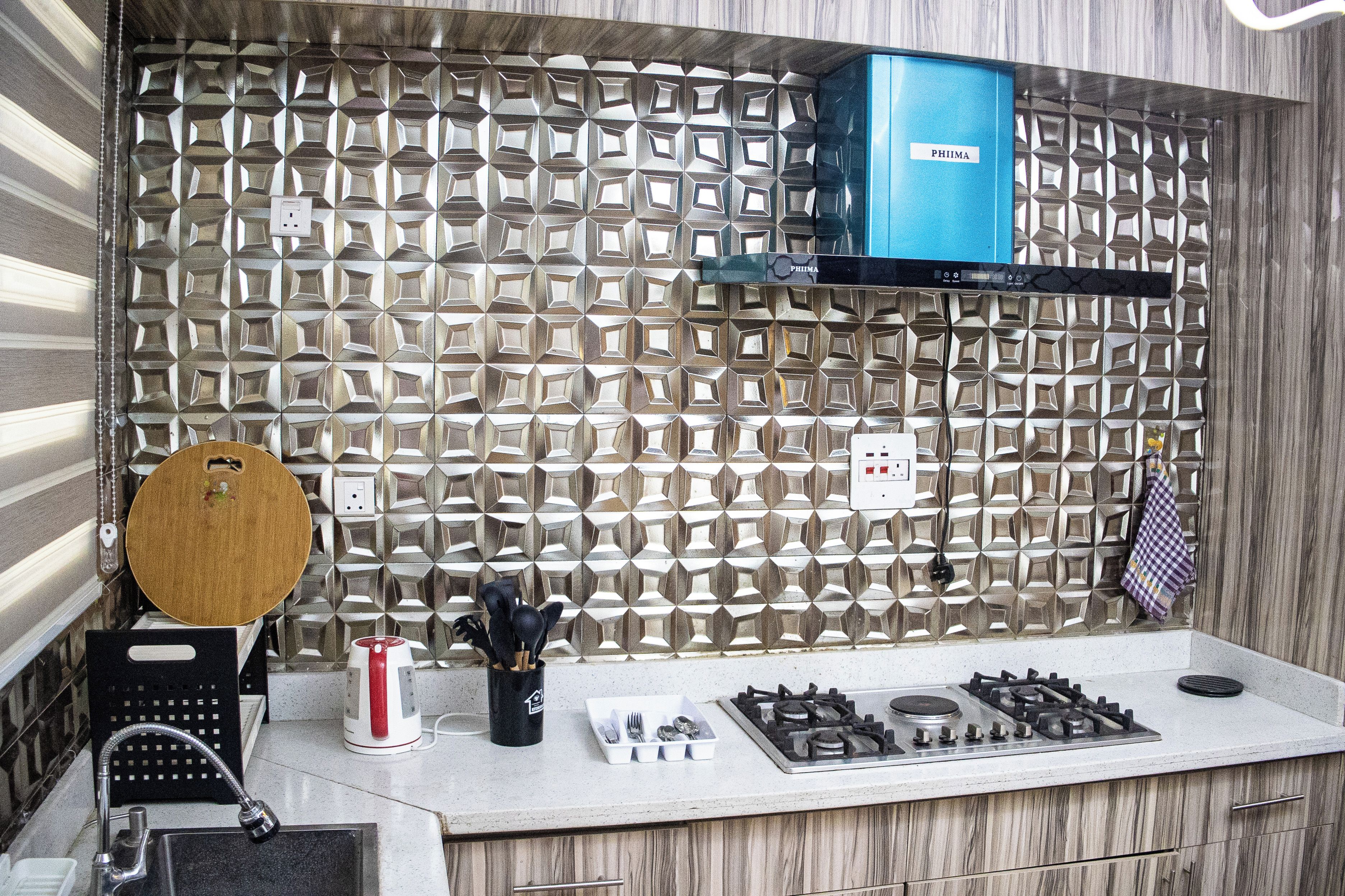 A kitchen with a geometric backsplash, a blue appliance, and various kitchen items.