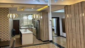 A modern kitchen with a central island, a dining area with a sofa, and a patterned wall. - Nigus House Oniru (Lagos)