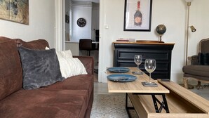 Una sala de estar con un sofá marrón, una mesa de centro de madera y una chimenea negra. Hay dos copas de vino y platos sobre la mesa.