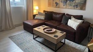 Una sala de estar con un sofá de cuero marrón, una mesa de centro de madera y una obra de arte con un mapa del mundo en la pared.