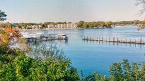 A waterfront view with a dock extending into the water, surrounded by trees and buildings in the background. - Relaxing Getaway, Lakeside Sunsets, 6 Waterpark passes, Memories Galore!! (Arnolds Park)