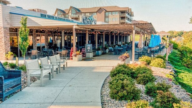 A hotel with a covered outdoor seating area, a pool, and a landscaped garden. - Relaxing Getaway, Lakeside Sunsets, 6 Waterpark passes, Memories Galore!! (Arnolds Park)