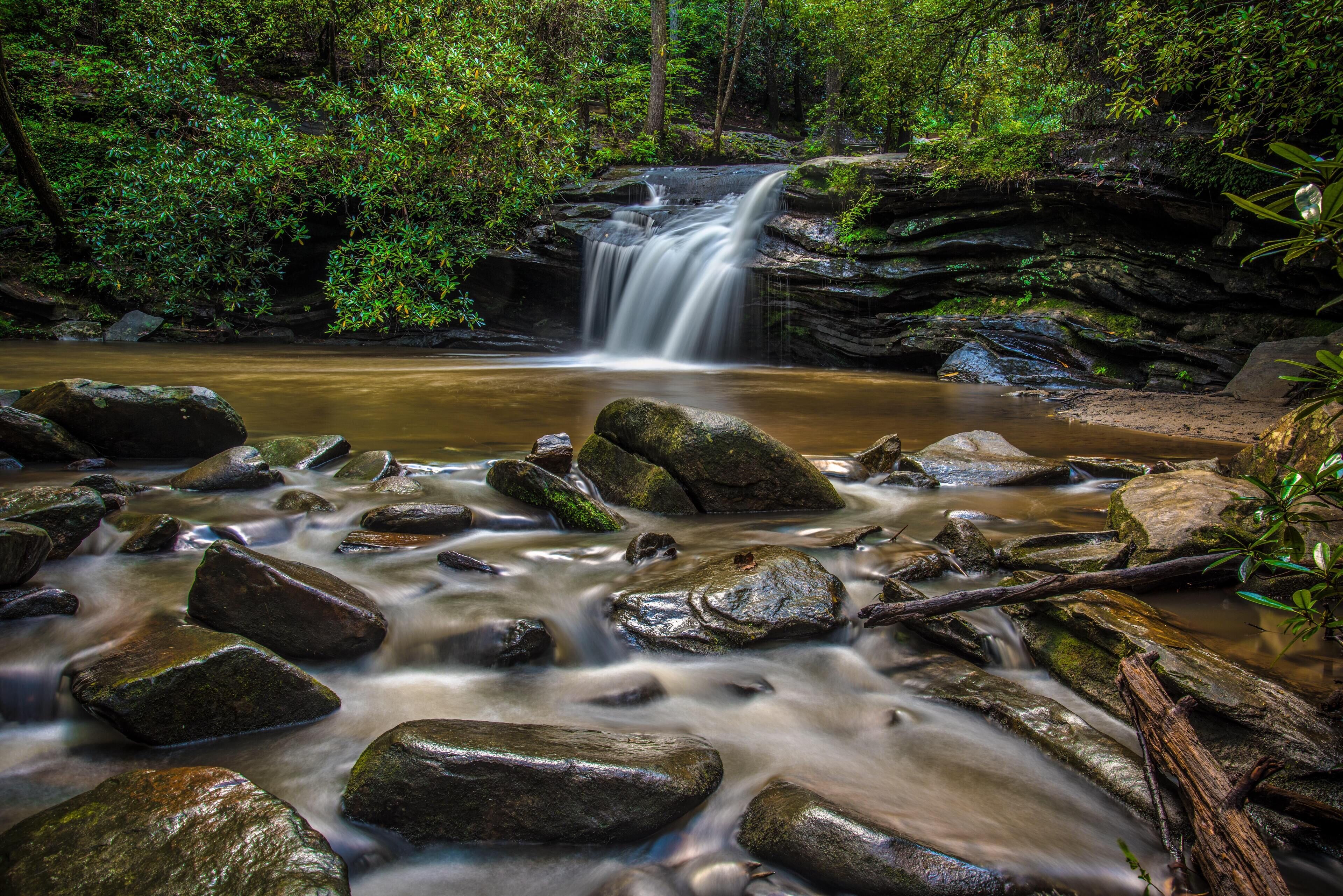 A waterfall surrounded by rocks and greenery.