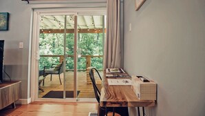 A room with a wooden desk, a chair, a television, and a sliding glass door leading to an outdoor deck. - Connects to Table Rock/Mountain View/Gigabit Wi-Fi/Covered Parking/Private Trail (Pickens)