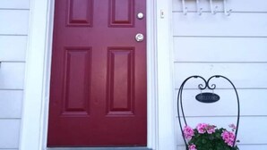 A red door with a mailbox and a welcome sign on the wall.