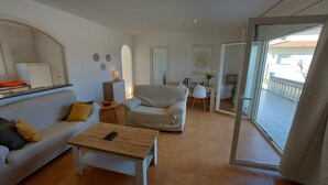 Ett modernt vardagsrum med en soffa, ett soffbord och en matplats med ett bord och stolar.