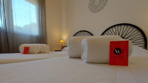 Ett hotellrum med två sängar, där varje säng har prydligt vikta handdukar och en röd etikett på en av sängarna.