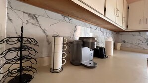 Eine Küche mit Marmor-Spritzschutz, einer Kaffeemaschine und einem Metallregal.
