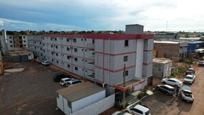 Il s’agit d’un bâtiment industriel à plusieurs étages, doté d’un toit rouge et de nombreuses fenêtres. On peut voir une enseigne indiquant « CM Hotel » au rez-de-chaussée.