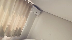 Un lit bien fait, avec une couverture marron et une serviette blanche nouée en forme de ruban, un oreiller blanc et une fenêtre avec des rideaux.