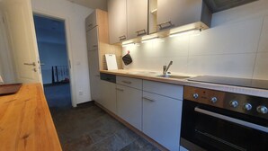 Een moderne keuken met witte kasten, een houten aanrecht, een roestvrijstalen spoelbak en een inbouwoven.