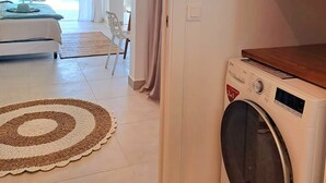 Une chambre d’hôtel moderne dotée d’un grand lit, d’une machine à laver et offrant une vue sur l’océan.