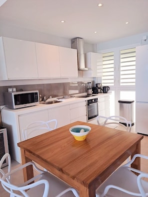 Enjoy cooking in this well-equipped kitchen with a stainless steel range hood, microwave, and blender.