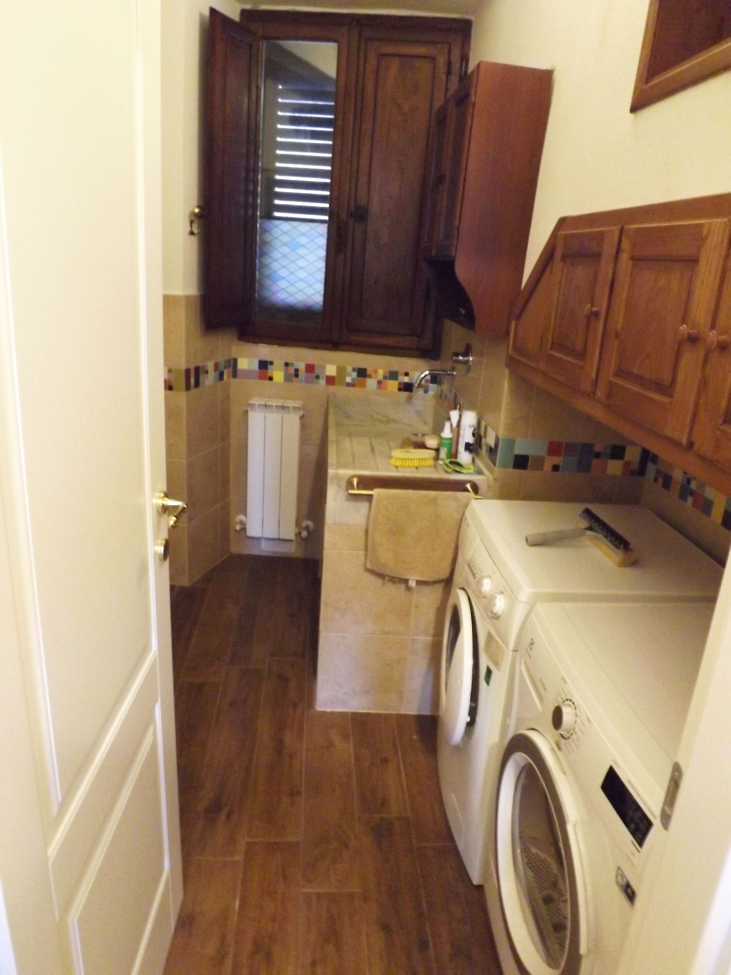 A compact kitchen with wooden cabinets, a washing machine, and a tiled backsplash.