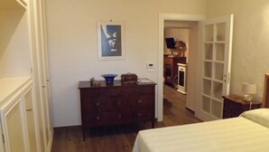 Une chambre à coucher comprenant un lit, une commode et une porte donnant sur une autre pièce.