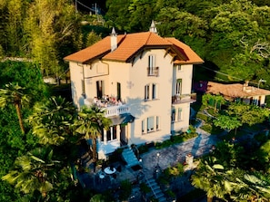 Un immeuble de deux étages doté d’un balcon, entouré d’une végétation luxuriante.