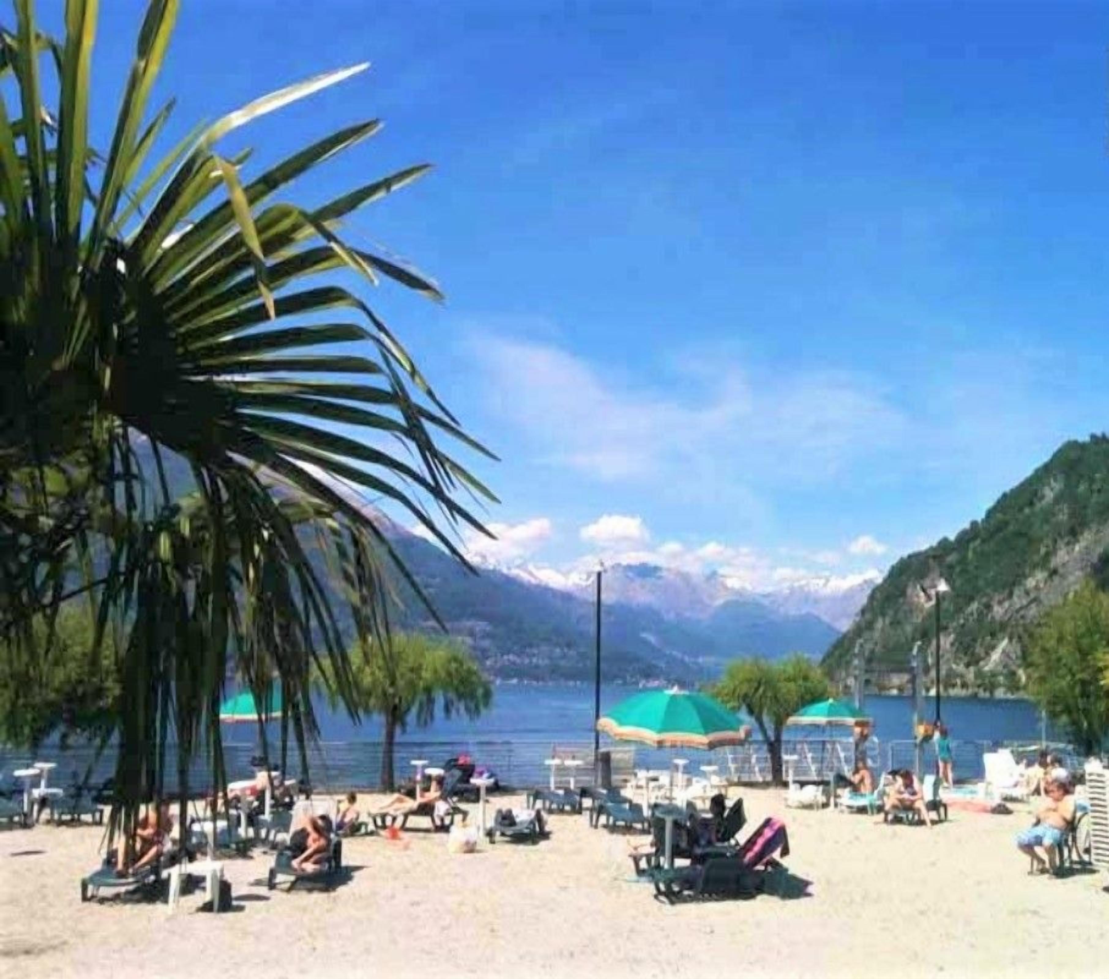 A beach with sun loungers, umbrellas, and a mountainous backdrop.