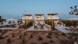 Un resort con tres edificios blancos, mobiliario exterior y una piscina.