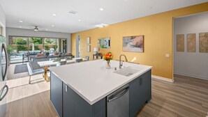 A modern kitchen with a central island, built-in appliances, and a dining area with a view. - Signature View! Gorgeous BRAND NEW Home (Misters!) (La Quinta)