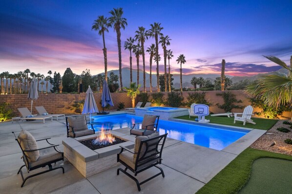A pool area with lounge chairs, a fire pit, and a basketball hoop. - Private pool & hot tub w/ mountain views (La Quinta)
