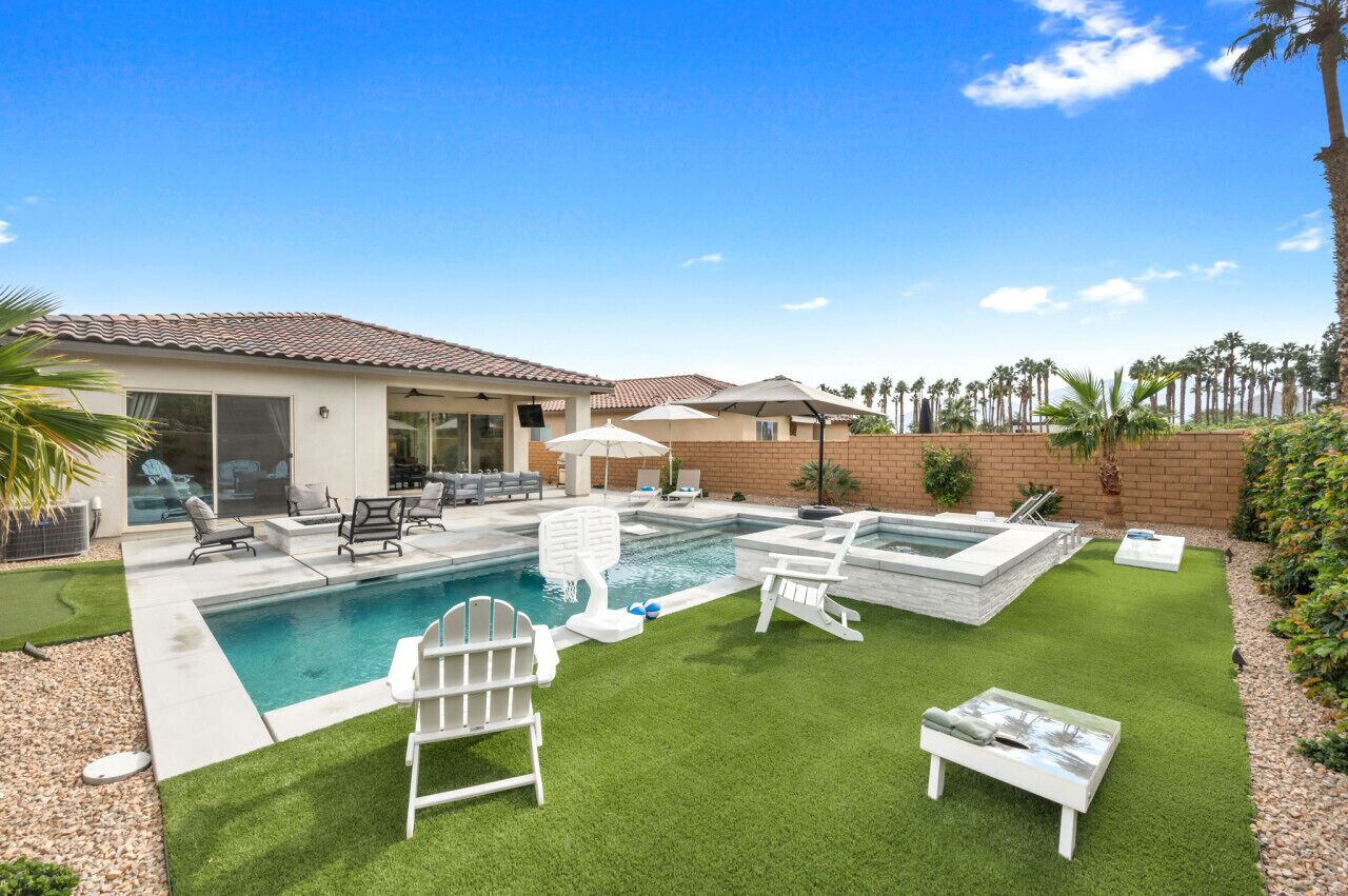 Un jardin avec une piscine, un espace salon extérieur et des palmiers.
