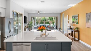 A modern kitchen with a large island, a dishwasher, and a refrigerator. - Signature View! Gorgeous BRAND NEW Home (Misters!) (La Quinta)