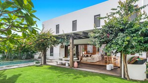 Une maison moderne dotée d’un patio, d’une piscine et d’une pelouse bien entretenue.