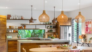 Une cuisine moderne dotée d’un îlot central, de meubles en bois et de luminaires suspendus en osier.