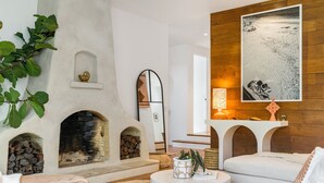 Un salon chaleureux avec une cheminée, des fauteuils confortables et un grand tableau accroché au mur.