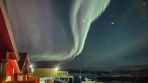A building with a dock and a view of the aurora borealis. - Lovely apartment in Offersøy with sauna (Offersøy)