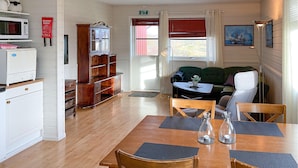 A cozy room with a wooden table, chairs, a sofa, a cabinet, and a microwave. - Lovely apartment in Offersøy with sauna (Offersøy)