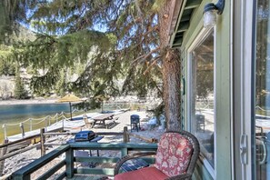 Situated by the water, this serene seating area offers a tranquil escape with a wooden bench and wicker chair.